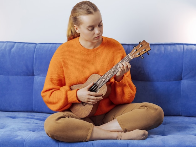 Premium Photo Girl Learns To Play The Ukulele At Home