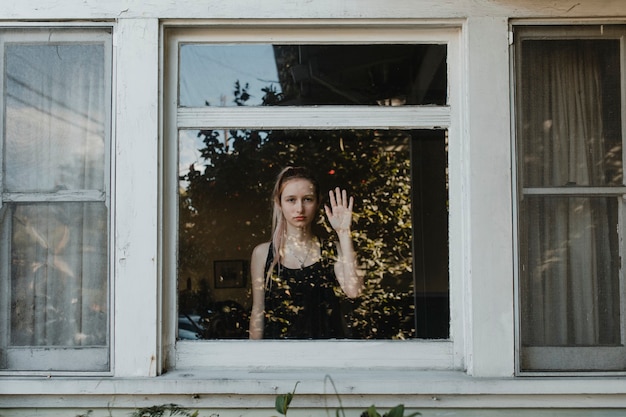 Premium Photo | Girl looking out the window of her la home during the ...