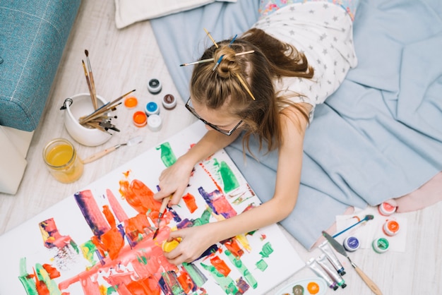 Girl lying on floor and painting with gouache Free Photo