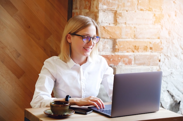 Girl manager, freelancer, business lady working on a laptop in a cafe ...