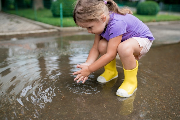 雨上がりの水たまりで遊ぶ女の子 プレミアム写真