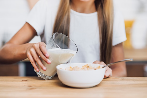 Premium Photo Girl Pouring Milk In A Cereal Bowl