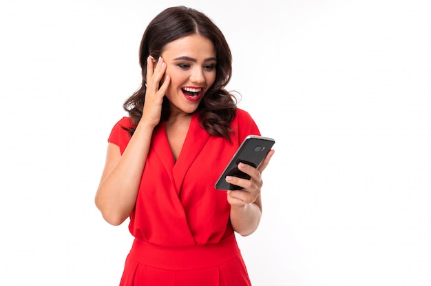 Girl in red overalls looks at the phone in surprise Premium Photo
