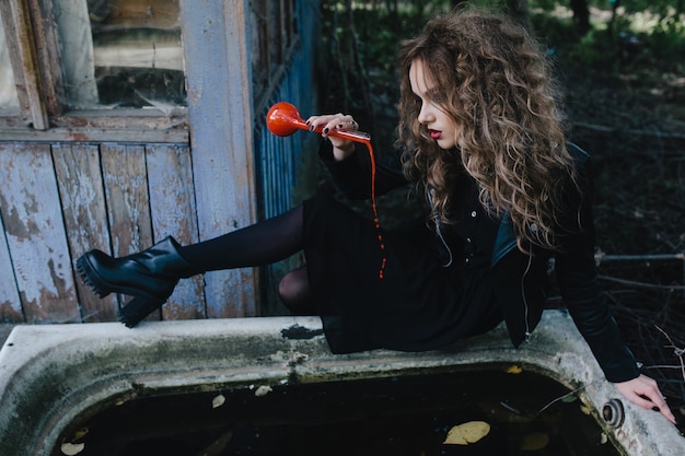 Free Photo | Girl sitting on the edge of a bathtub with a red potion