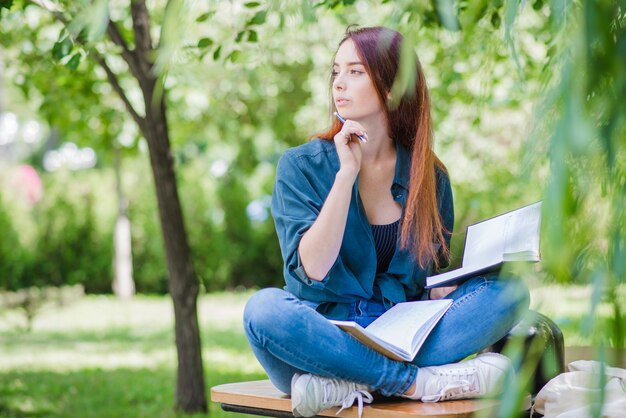 Free Photo | Girl sitting in park studying looking away