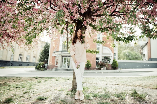 建物の桜の木の近くに立っている女の子 無料の写真