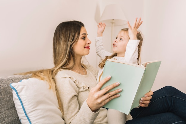 Girl telling story to mom while reading book Free Photo