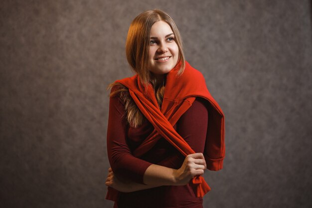 Premium Photo Girl Tries On A Red Sweater On A Gray Background