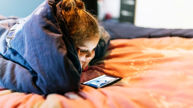 Free Photo | Girl using smartphone under blanket