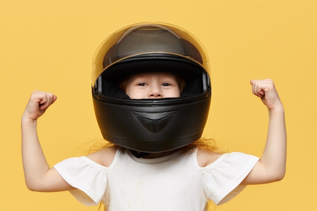 上腕二頭筋を示す黒い安全バイクのヘルメットをかぶった女の子 無料の写真