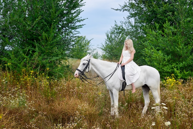 Premium Photo | Girl in white dress riding a horse in the field