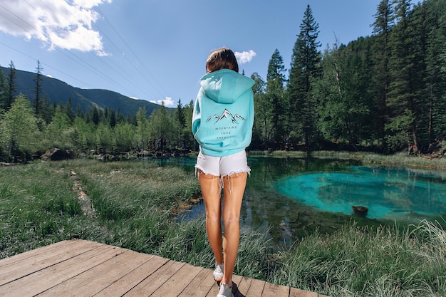 Premium Photo Girl With Brown Hair In Blue Hoodie And Short White Shorts Stands On Wooden 9277