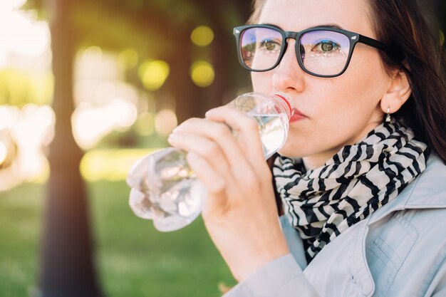 Premium Photo Girl With Glasses Drinks Mineral Water From A Plastic