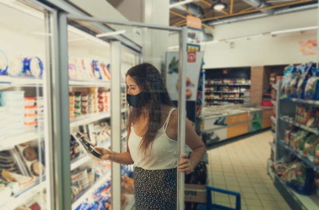 Download Premium Photo Girl With A Mask Opening A Fridge At The Supermarket