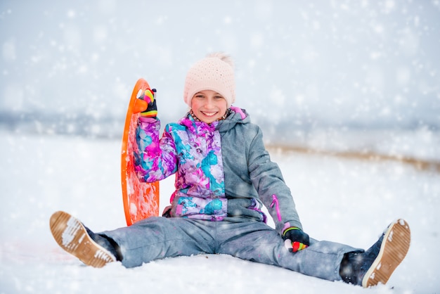 Premium Photo | Girl with saucer sled on the snow