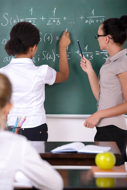 Premium Photo | The girl writes on the board an example of a teacher helps.