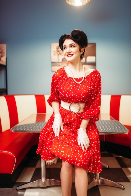 メイク レトロなカフェのインテリア 50のアメリカンファッションとグラマーピンナップガール ビンテージスタイルの水玉模様の赤いドレス プレミアム写真