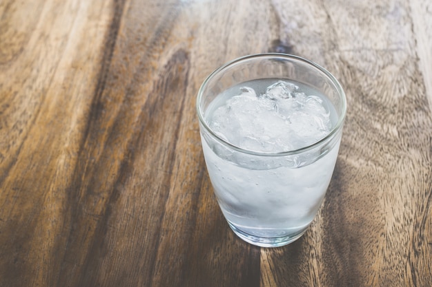 Premium Photo | Glass of fresh mineral water with ice cubes on wood table with vintage color
