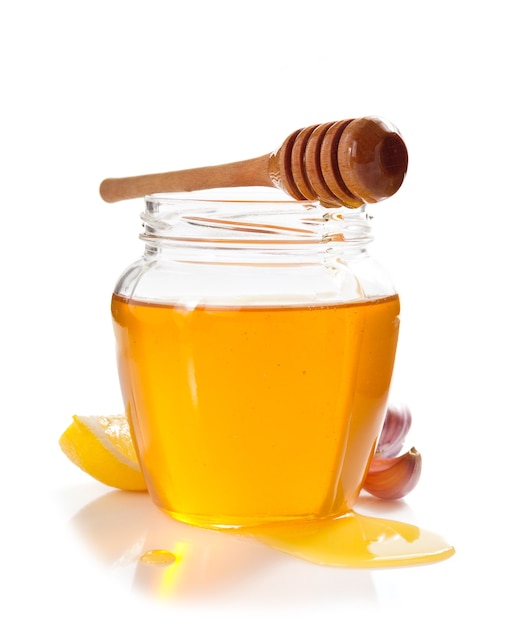 Premium Photo | Glass jar full of honey and dipper isolated on white