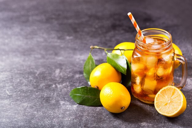 Premium Photo | Glass jar of iced tea with fresh lemons on dark