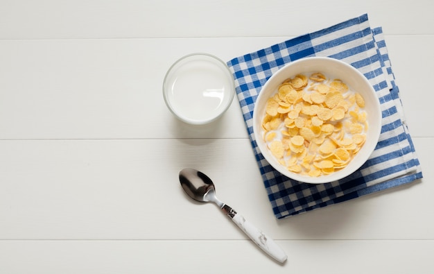 Glass of milk next to bowl of cereals on cloth Free Photo