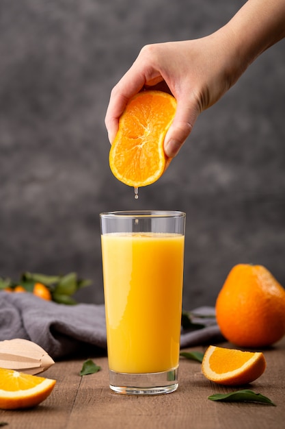 オレンジジュースのグラスとオレンジを絞る人 無料の写真