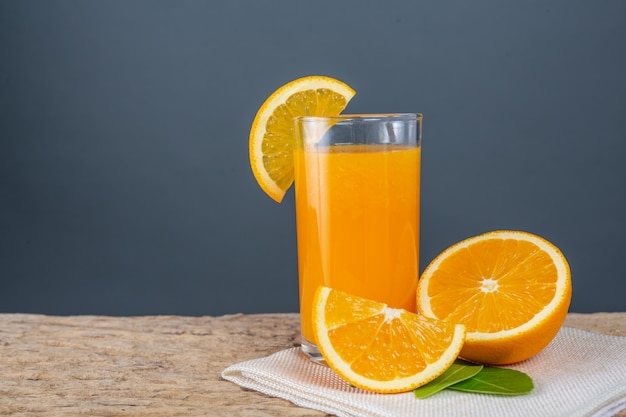 オレンジジュースのグラスを木の上に置きます 無料の写真