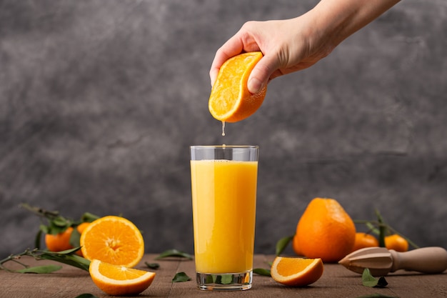Glass of orange juice and a person squeezing an orange in it Free Photo
