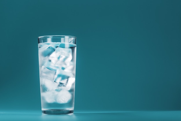 Premium Photo A Glass With Ice Water And Ice Cubes On A Blue Surface