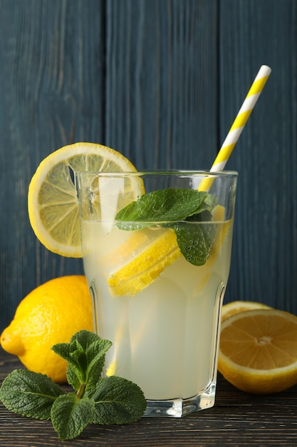 Premium Photo | Glass with lemonade and lemons on wooden surface. fresh ...