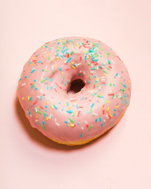 Free Photo | Glazed donut with sprinkles on pink surface