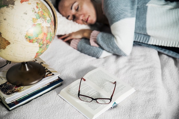 Globe and books near sleeping woman Free Photo