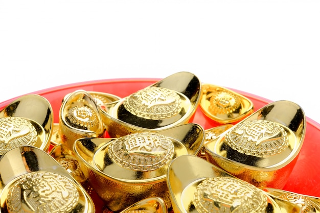 Golden ingots on red tray isolate at white.chinese language on ingot mean Premium Photo