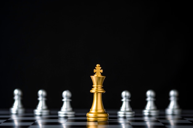 チェス盤と黒の背景に銀のポーンチェスの前にゴールデンキングチェス プレミアム写真