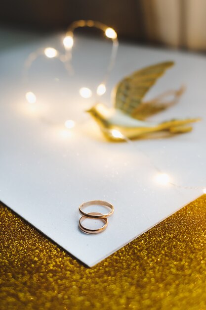 Premium Photo | Golden wedding rings on golden background with decorations.