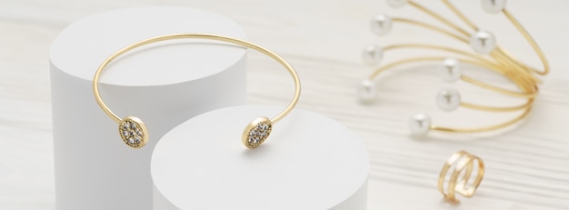 Premium Photo | Golden with diamonds bracelet on white platforms and ...