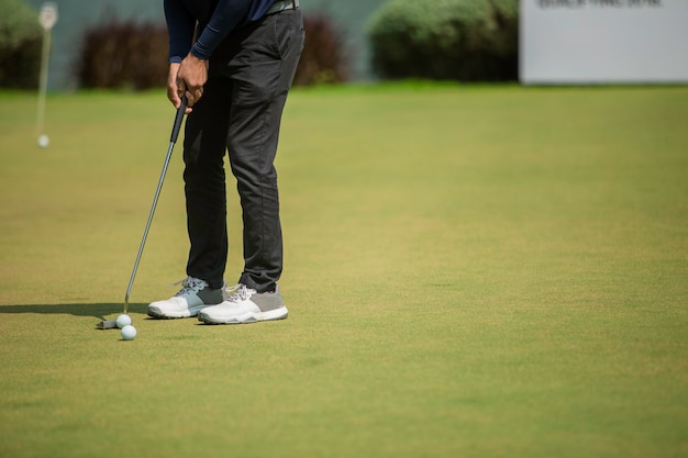 Premium Photo | Golf player at the putting green hitting ball into a hole