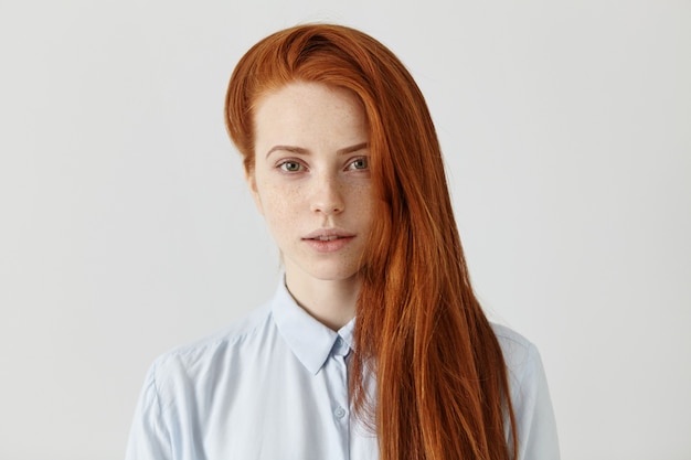 水色のフォーマルシャツを着て長い緩やかな髪型を持つ豪華な赤毛の学生の女の子 無料の写真