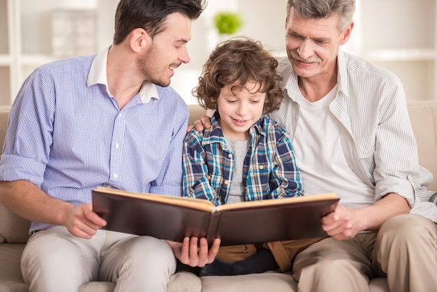 Premium Photo Grandfather Father And Son Sitting And Reading Book On