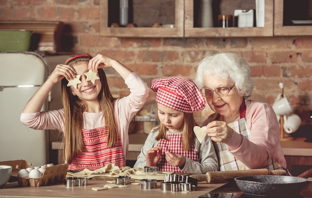 Premium Photo | Grandma teaching granddaughters to bake cookies