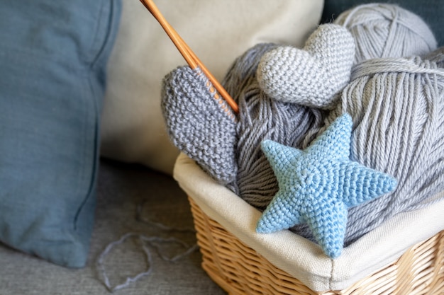 Premium Photo Gray Balls Of Wool And Knitting Needles In A Wicker Basket Stand On A Gray Sofa With Pillows