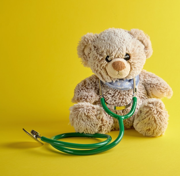 Premium Photo | Gray teddy bear and green medical stethoscope on a yellow