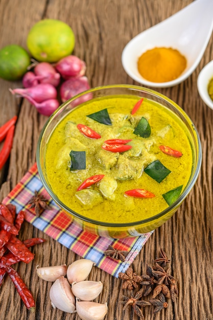 Free Photo | Green curry in a bowl and spices on wooden table.