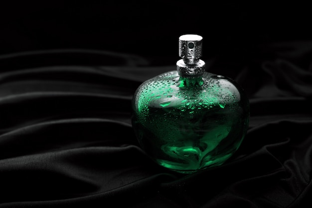 Premium Photo | Green perfume on black background