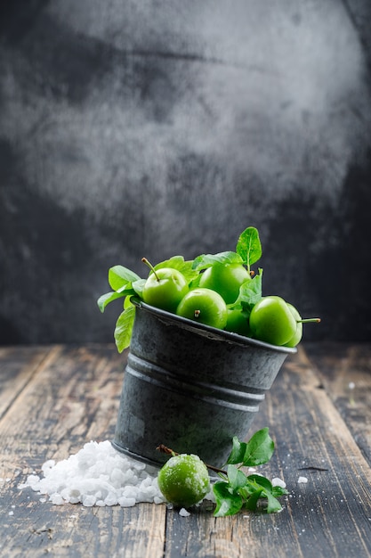 Free Photo | Green plums in a mini bucket with salt crystals, leaves ...