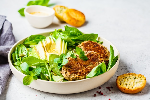 Green salad with avocado, cucumber and lentil patties in white plate. Premium Photo