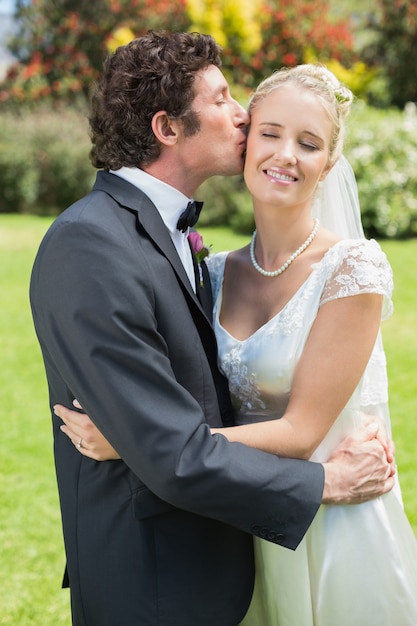 Premium Photo | Groom kissing his pretty new wife on the cheek