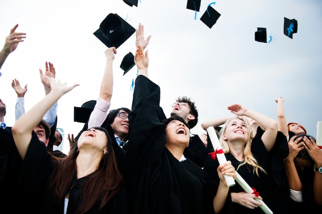 Group of diverse grads throwing caps up in the sky Free Photo