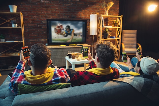 Group of friends watching tv, sport match together. emotional fans cheering for favourite team, watching exciting football. concept of friendship, leisure activity, emotions. Free Photo