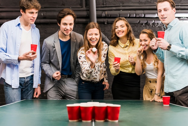 Free Photo | Group of happy smiling friends enjoying beer pong game on  table in bar